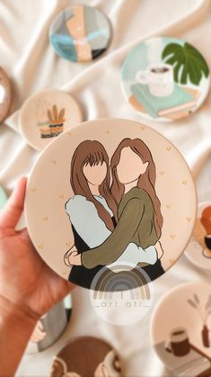 two women hugging each other in front of many coffee cups and plates on a table