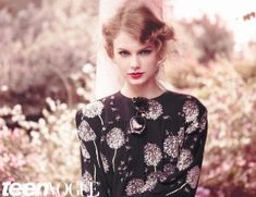 a woman standing in front of flowers wearing a black and white floral print dress with long sleeves