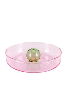 a pink glass bowl with a green ball in the center on a white background,