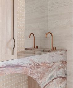 a bathroom with marble counter tops and gold faucets on the wall above it