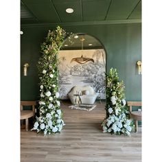 an archway decorated with flowers and greenery in the middle of a room that is painted green