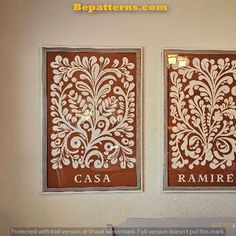 two wall hangings with decorative designs on the side of each one, in white and brown