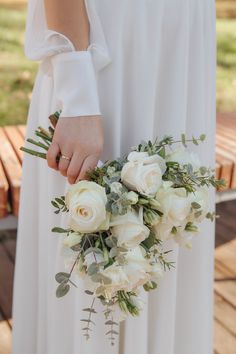 a bride holding a bouquet of white roses