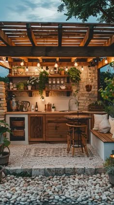 an outdoor kitchen with potted plants on the counter and lights hanging from the ceiling