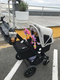 a baby stroller sitting in the middle of a parking lot next to a pier