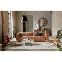 a living room filled with furniture next to a window and potted plant on top of a rug