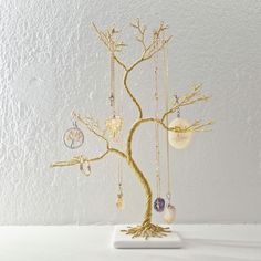 a gold tree with several ornaments hanging from it's branches, on a white surface