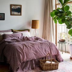 a bed in a bedroom next to a potted plant