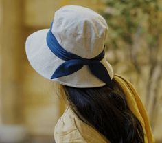 a woman wearing a white hat with a blue bow on it's brim