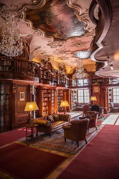 the library has many bookshelves and chandeliers