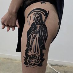 a woman with a tattoo on her thigh holding a cross and a rose in front of her leg