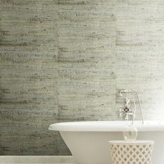 a white bath tub sitting next to a wall with a textured pattern on it