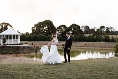 a bride and groom standing in front of a pond