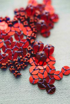 some red and blue beads are laying on a table cloth with one bead in the middle