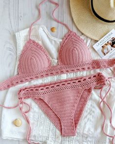 a woman's pink bikinisuit and hat laying on top of a white table