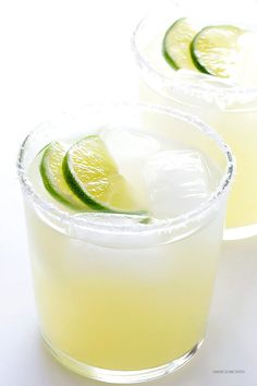 two glasses filled with lemonade and lime slices