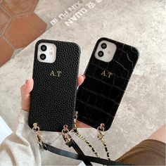 two cell phones with chains attached to them, one is black and the other is white