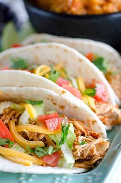 three shredded chicken tacos on a blue plate