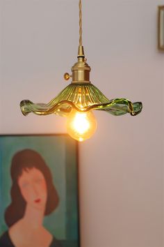 a light that is hanging from the ceiling in front of a painting on the wall