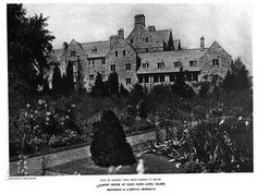 an old black and white photo of a large house with lots of flowers in the front yard