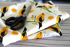 a pair of scissors sitting on top of a white and yellow cloth with black handles