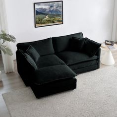 a black couch sitting on top of a white rug in a living room next to a window