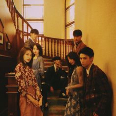 a group of young people standing in front of a stair case next to each other