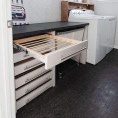 an open drawer in a kitchen next to a washer and dryer