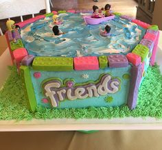 there is a cake with people in the pool on it and grass around it that says friends