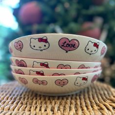 three hello kitty bowls sitting on top of a wicker place mat next to a christmas tree