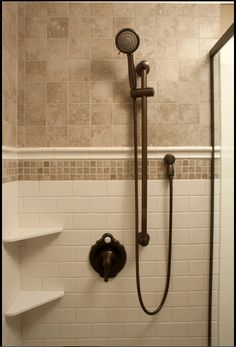 the shower head is mounted on the wall above the toilet and shelves in the bathroom