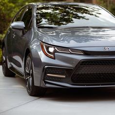 the front end of a gray car parked on a driveway