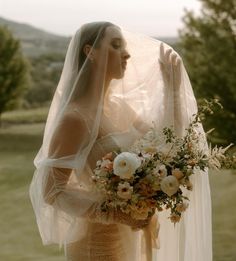 a woman wearing a veil holding a bouquet of flowers