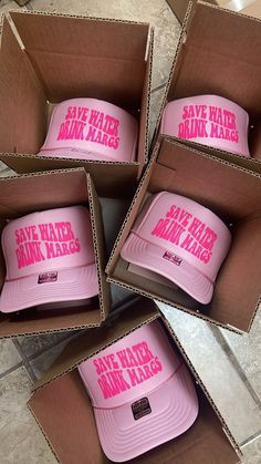 six pink hats are in a box on the floor, with save water drink milk