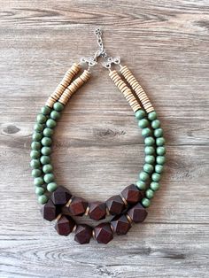 A lightweight beaded multi strand statement necklace made with dark brown and olive green wood beads and beige coconut wood beads. - Shortest strand is 20.5-22.5".- Stainless steel lobster claw clasp (gold stainless, sterling silver, gold filled are also available)- 2" Stainless steel extender chain- Lead free pewter multi strand connectors - Largest bead measures 20mm (.78")The length can be customized. The mannequin's neck size is 15". Larger quantities may be available. Please let us know how many you need.All DLD jewelry comes in a silver jewelry box for gift giving. We use the highest quality findings to ensure a piece that will last for years to come. DLD jewelry comes with a lifetime guarantee. This necklace is handmade in the USA. Dana LeBlanc Designs- Handmade Jewelry Green Statement Necklace, Coconut Wood, Silver Jewelry Box, Wood Bead Necklace, Wood Necklace, Green Wood, Chunky Necklace, Multi Strand, Wood Beads