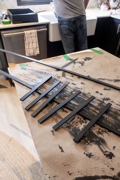 a man standing in front of a table with pieces of wood on top of it