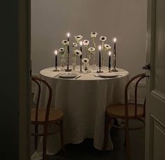 a table with candles and flowers on it in front of a doorway that leads to another room