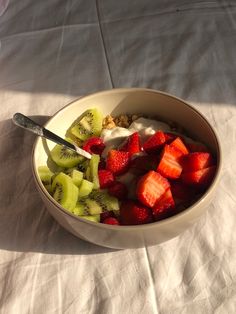 a bowl filled with fruit and yogurt on top of a white table cloth