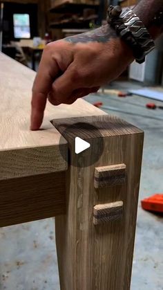 a person is making a house out of wooden planks with their thumb on the table