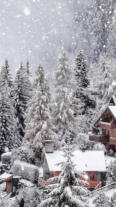 a snowy scene with houses and trees in the foreground, snow falling on the ground