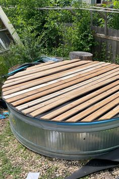 A wood-slatted cover is sitting on top of a metal stock tank pool. Stock Tank Pool Cover, Water Trough Pool, Stock Tank Pool Deck, Plastic Stock Tanks, Stock Tank Pool Ideas