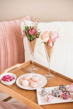 two vases filled with flowers sitting on top of a table next to plates and candy