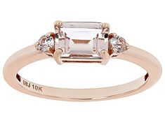 a rose gold engagement ring with an emerald stone and three diamonds on the band, set in