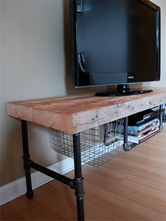 a flat screen tv sitting on top of a wooden table next to a wire basket