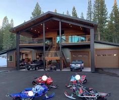 three snowmobiles are parked in front of a large house with two decks on the roof