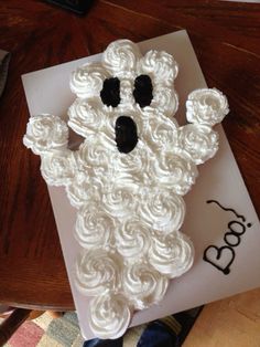 a cake made to look like a ghost on top of a card with the word boo spelled out