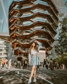 a woman standing in front of a tall building with lots of stairs on it's sides