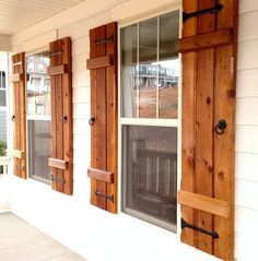 two windows with wooden shutters on the side of a house