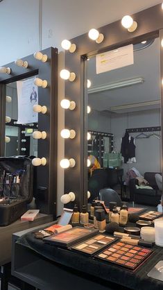 a mirror that has some lights on it in front of a table with makeup and other items