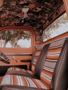 the interior of an old red truck with pictures on the ceiling and leather seat covers